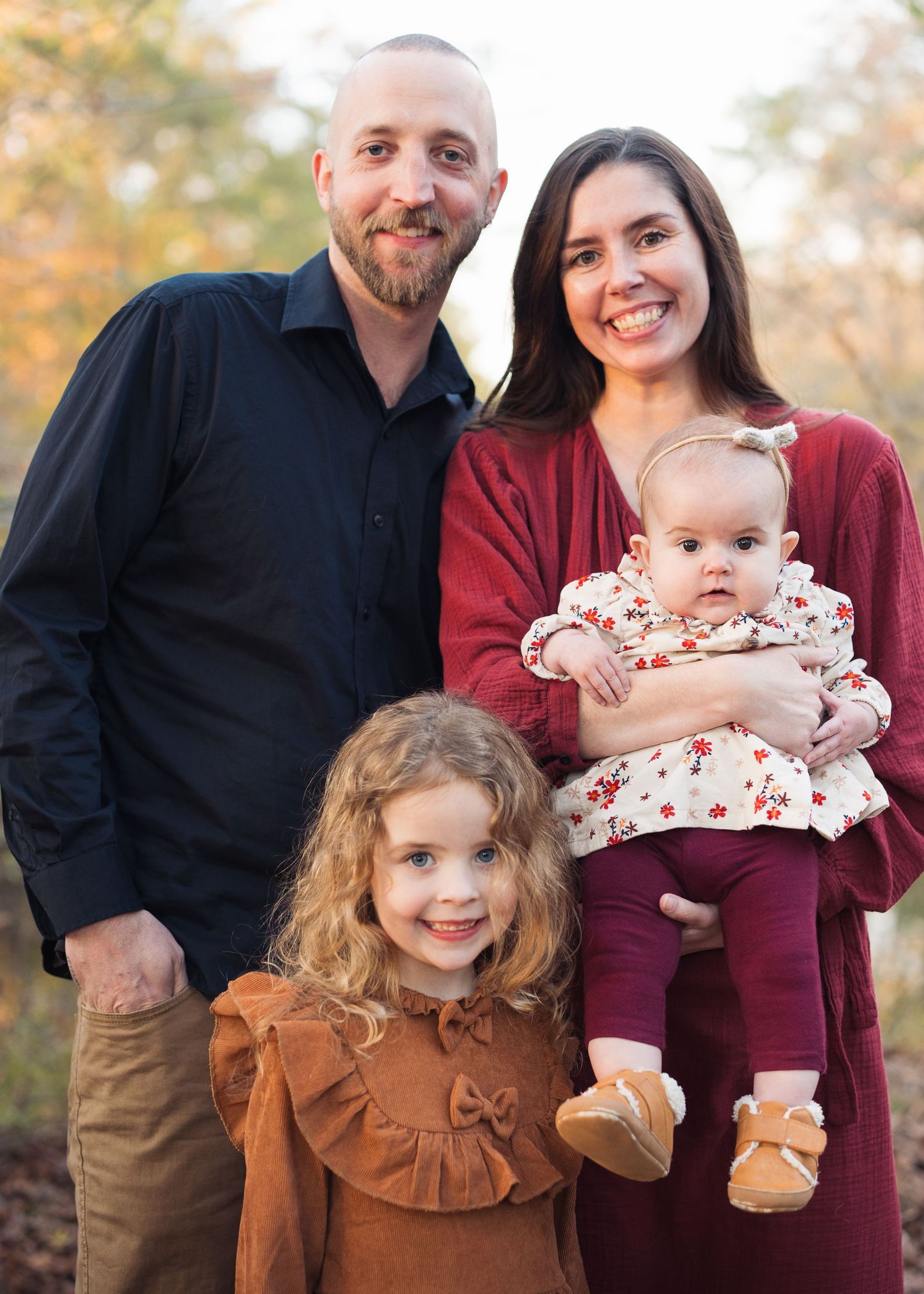 Happy family of four smiles together in warm autumn outdoor portrait setting in Chattanooga, TN.