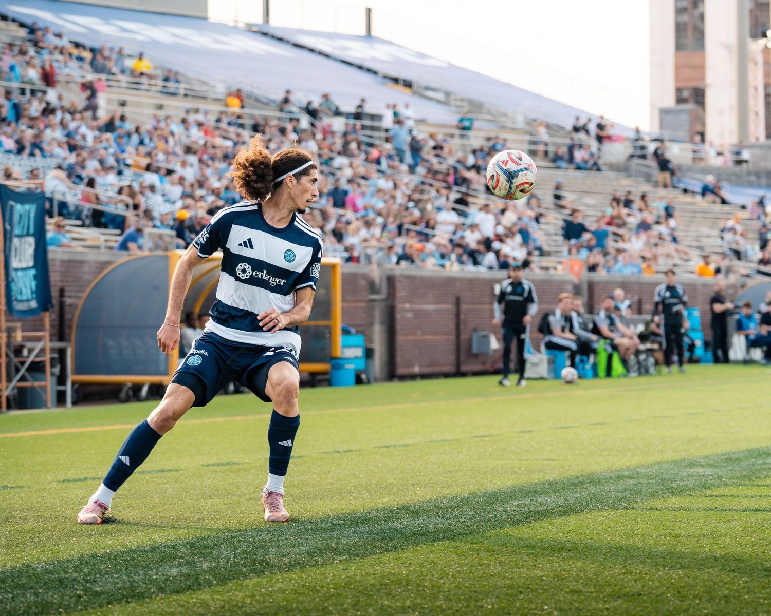 Chattanooga FC Soccer player controls the ball near the sideline during a professional MLS Next Pro match in a packed stadium.