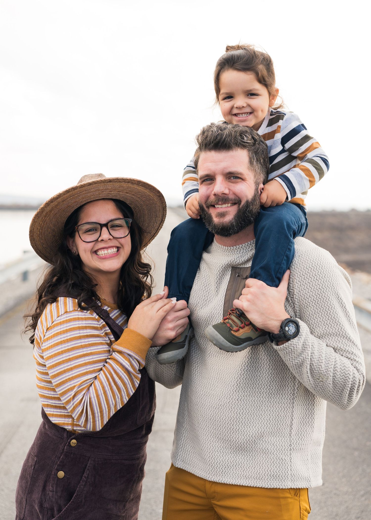 Happy family of three posing outdoors, child sitting on fathers shoulders in Chattanooga, TN.