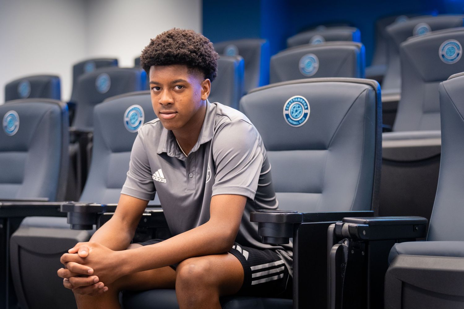 Young soccer player in polo sits in stadium seating at a professional sports facility Photographed for Chattanooga FC player signing.