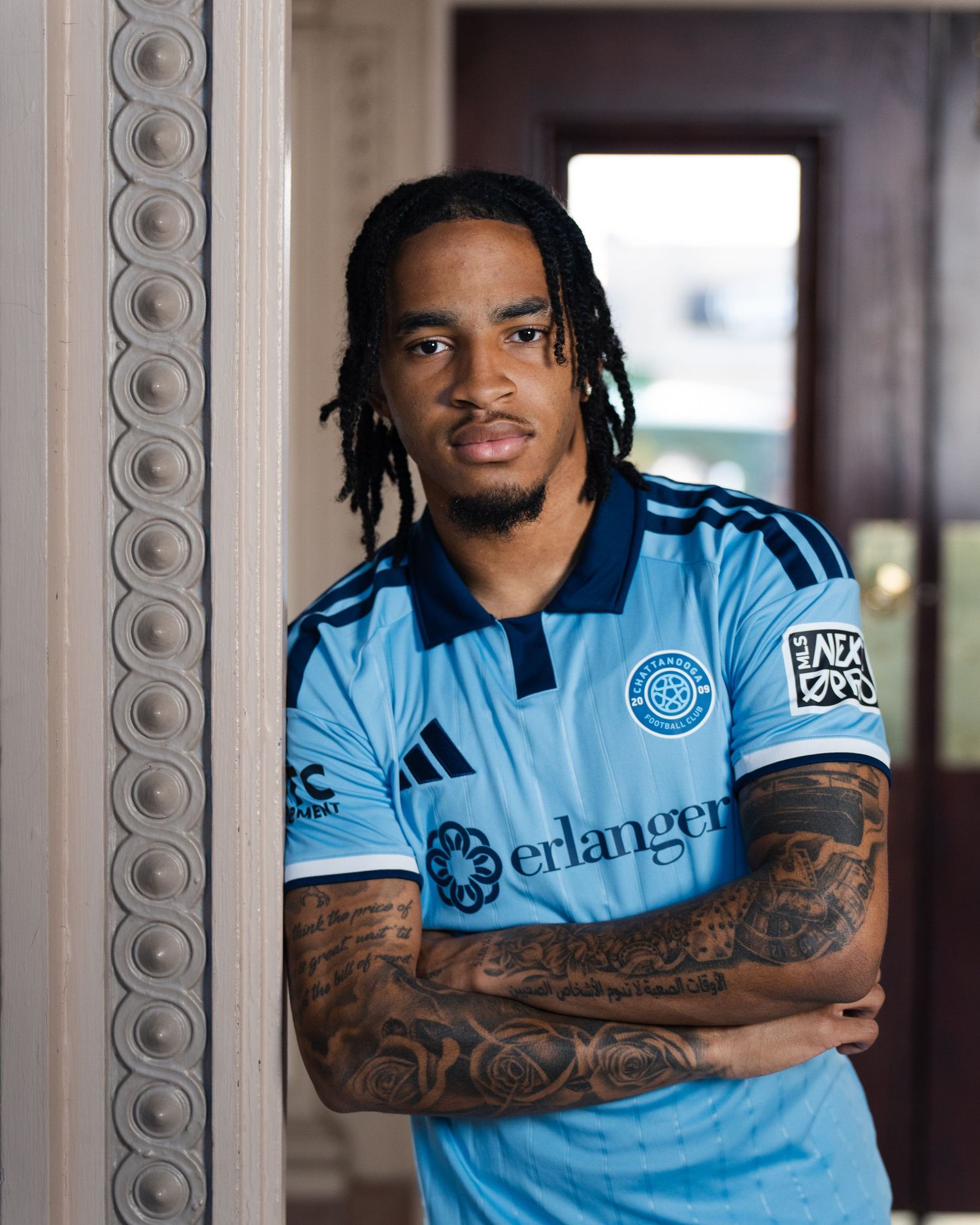 Tattooed Chattanooga FC player poses in jersey leaning against column photographed for a creative sports assignment in Chattanooga, TN.