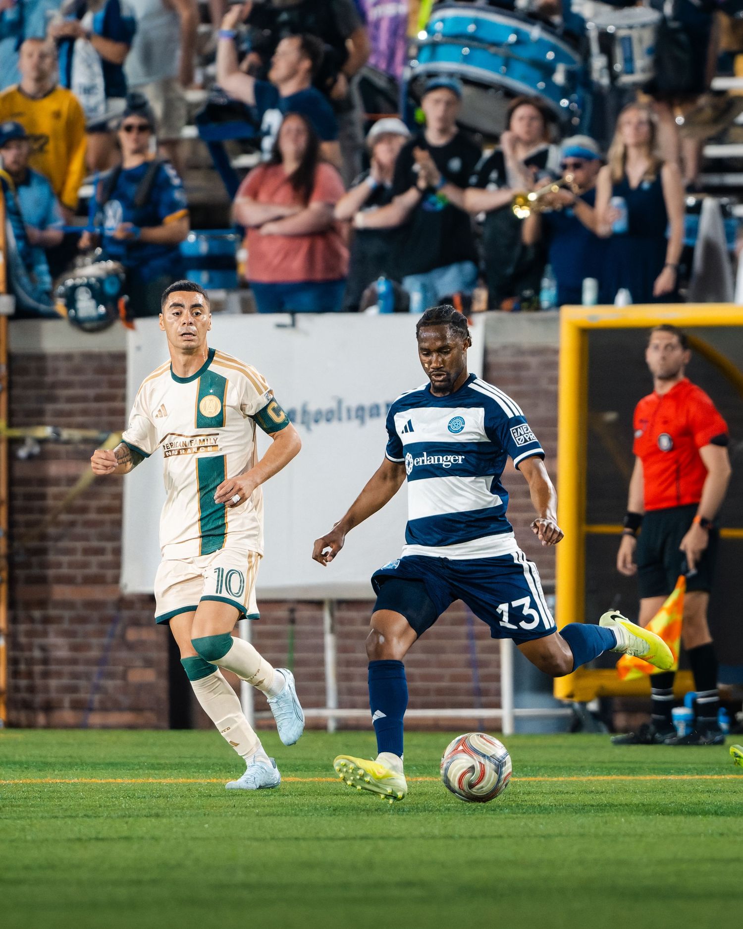 Chattanooga FC Soccer player in navy blue kit dribbles ball past opponent during an evening U.S. Open Cup match with fans watching.