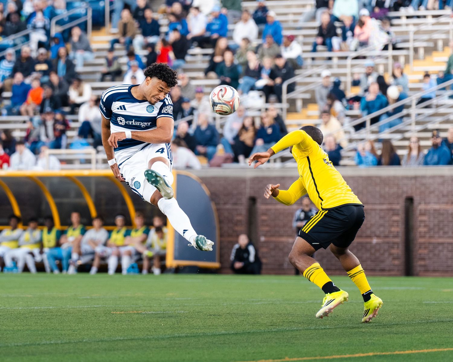 Chattanooga FC Soccer player in navy blue jersey wins a header against an opponent from Columbus Crew 2.