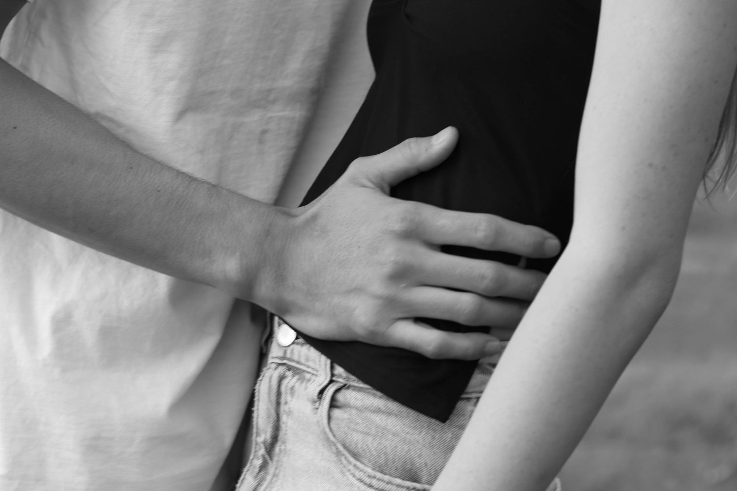 Close-up black and white photo of couple embracing, mans hand on womans waist.