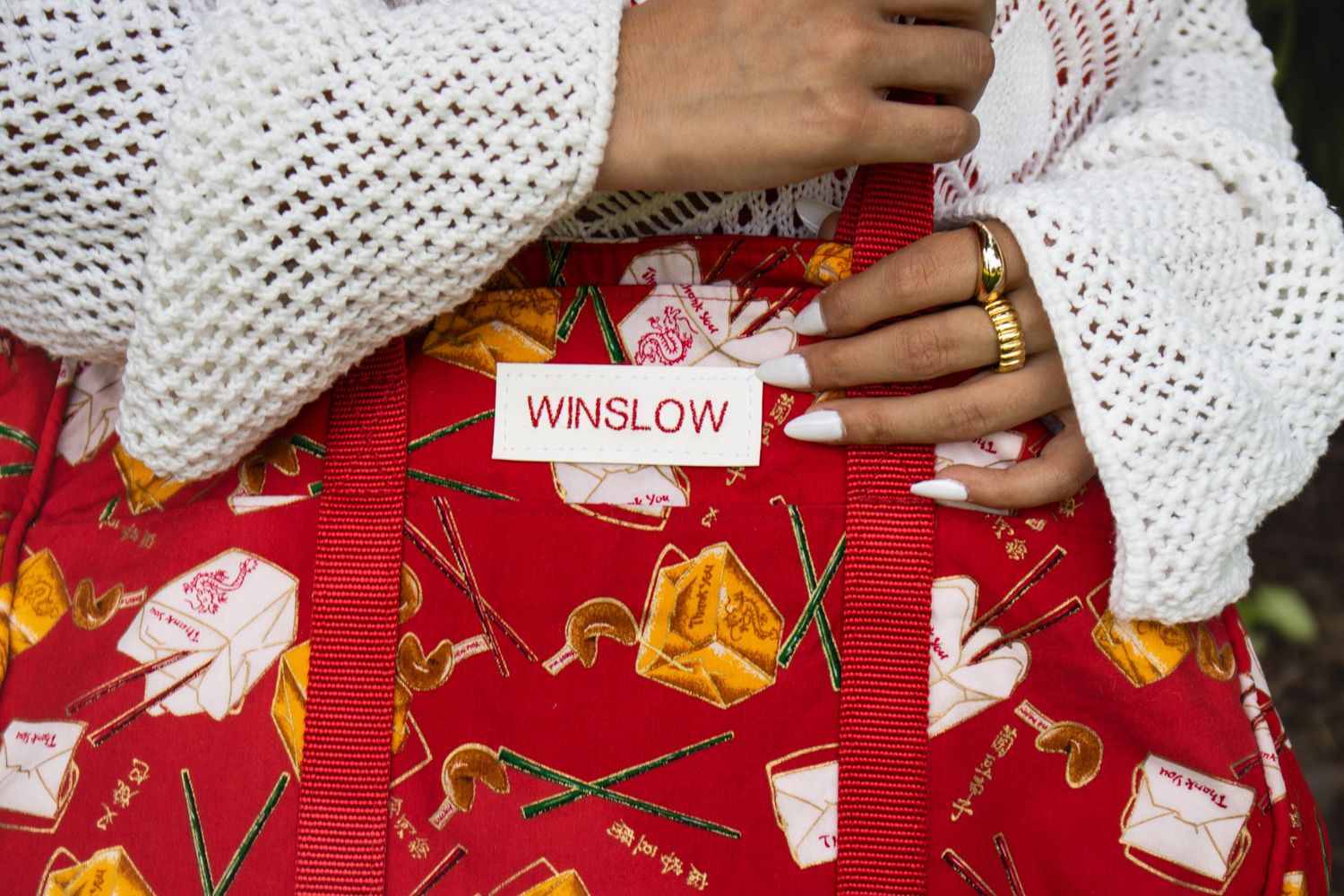 Close-up of a red Winslow tote bag with colorful Chinese food pattern and white brand label.