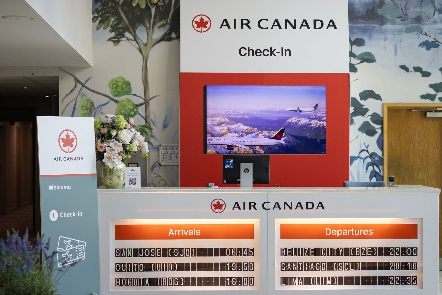 Air Canada check-in desk displaying arrivals and departures boards in a hotel lobby.