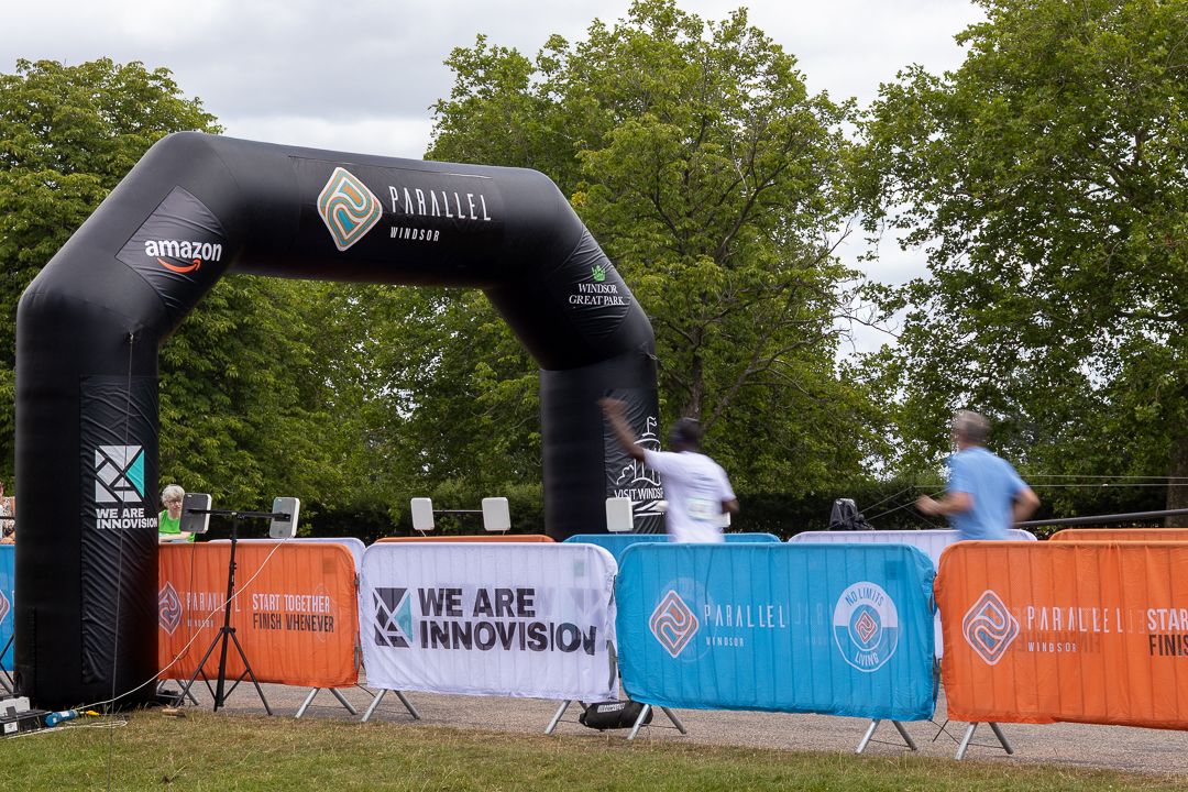 Inflatable arch at Parallels Amazon running event with 'We Are Innovision' banner and participants in background.