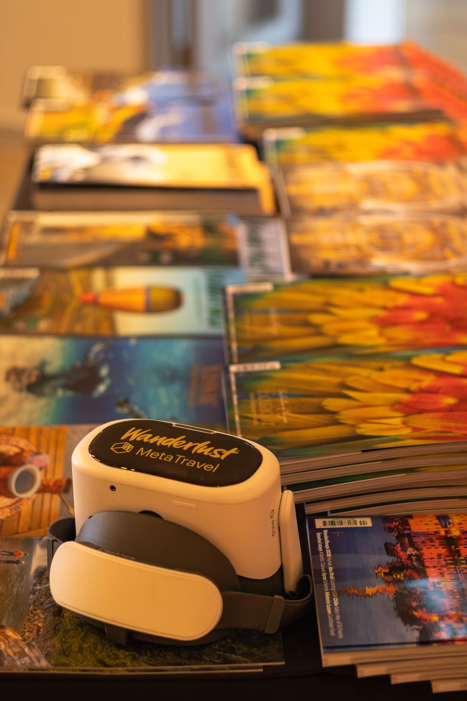 Wanderlust MetaTravel VR headset on a table surrounded by colorful travel magazines.