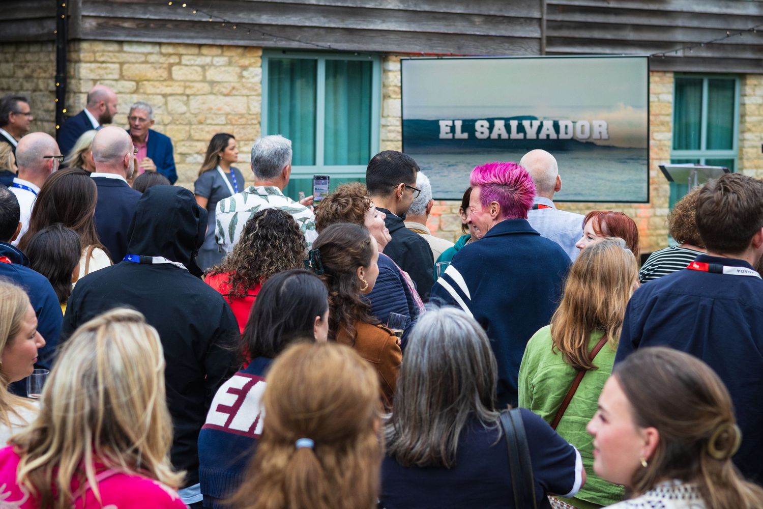 Large crowd gathered outside El Salvador restaurant for an outdoor event on a cloudy day.