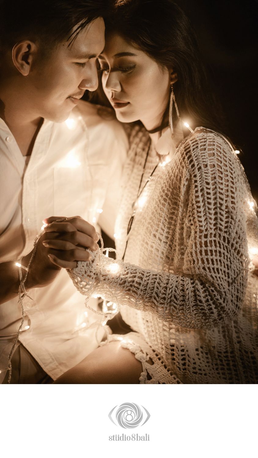Romantic couple wrapped in fairy lights sharing an intimate moment, shot by Studio 8 Bali photographers.