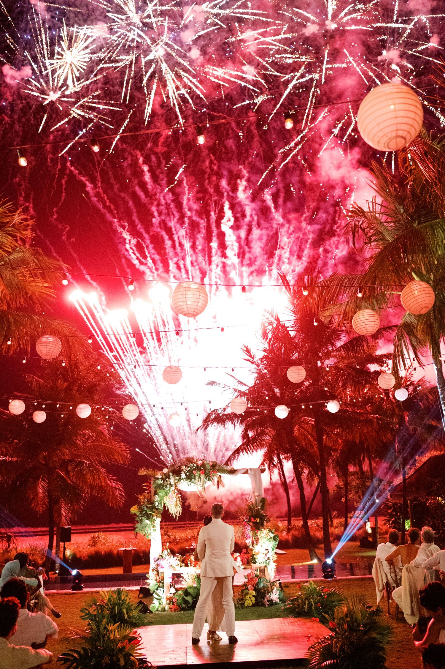 Couple watches stunning fireworks light up the night sky over their tropical destination wedding venue.