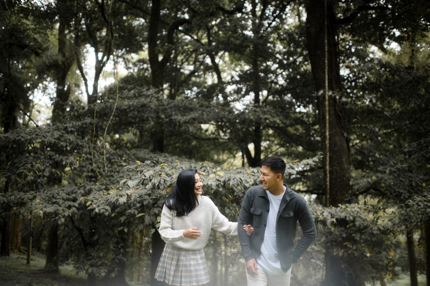 Couple walking and talking together in a lush green forest park setting.