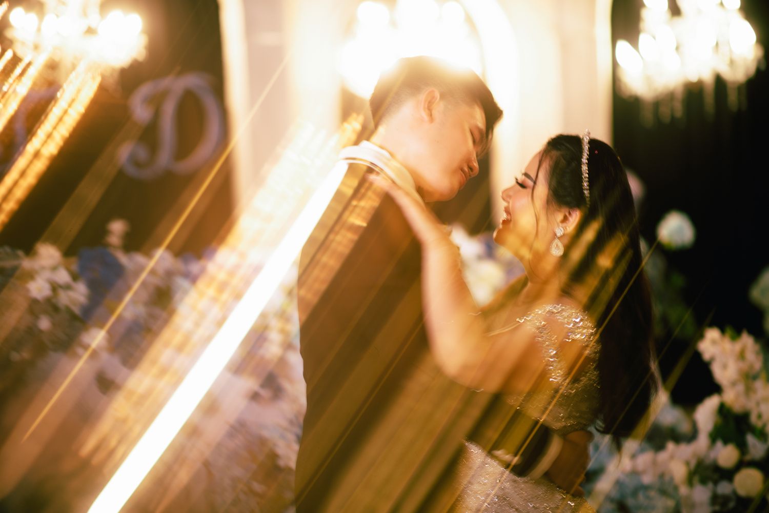 A couple shares a romantic first dance at their wedding reception, bathed in warm golden bokeh lights.