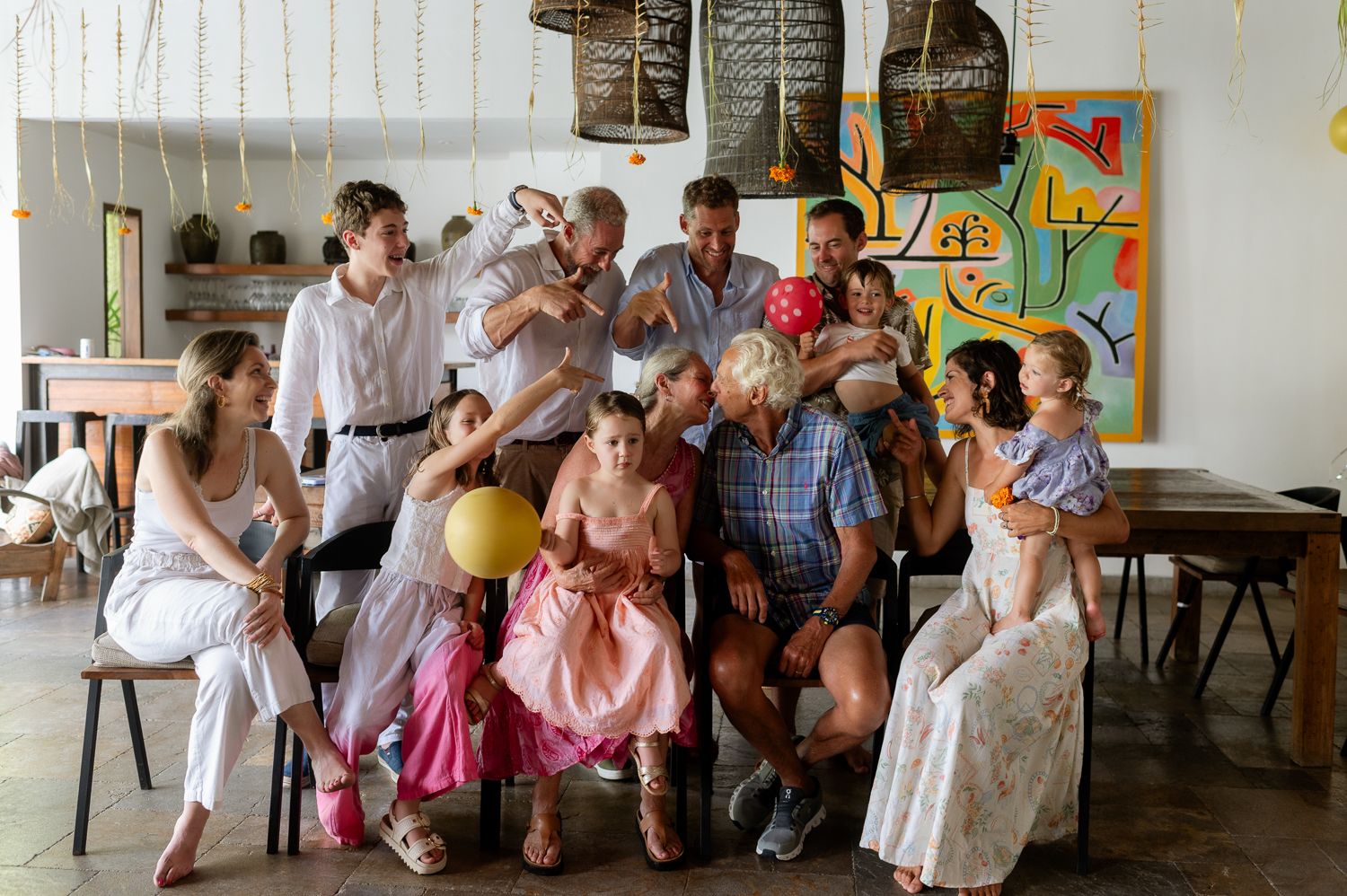Large joyful family group posing together in a bright decorated room during a festive celebration.