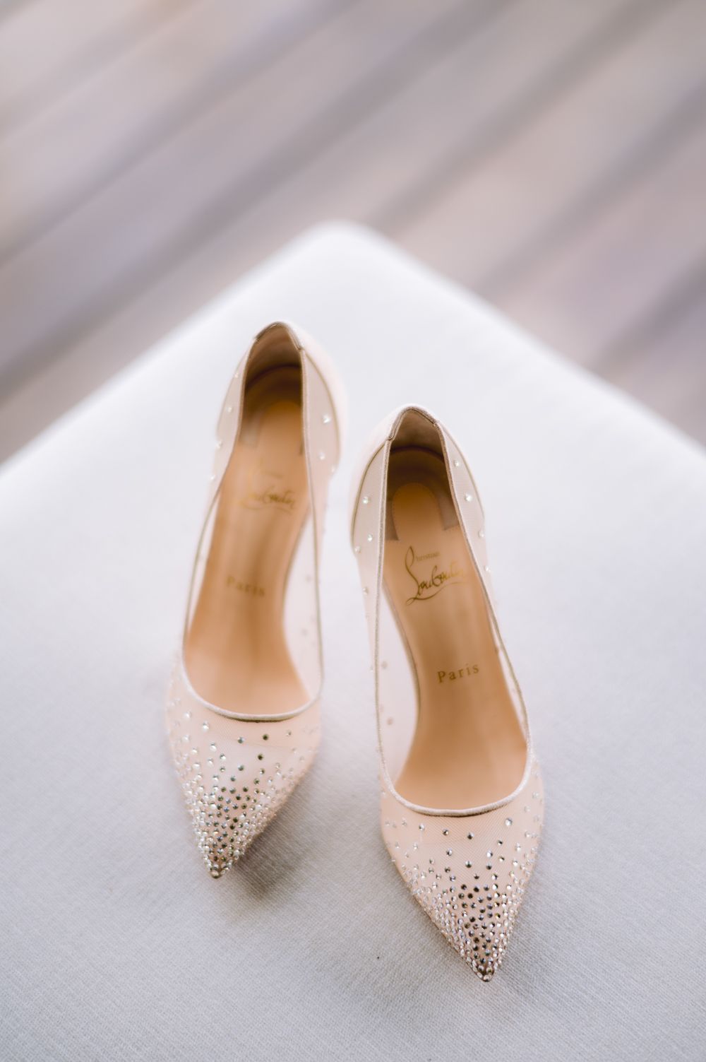 Elegant Christian Louboutin nude crystal-embellished pointed-toe heels displayed on a white surface.