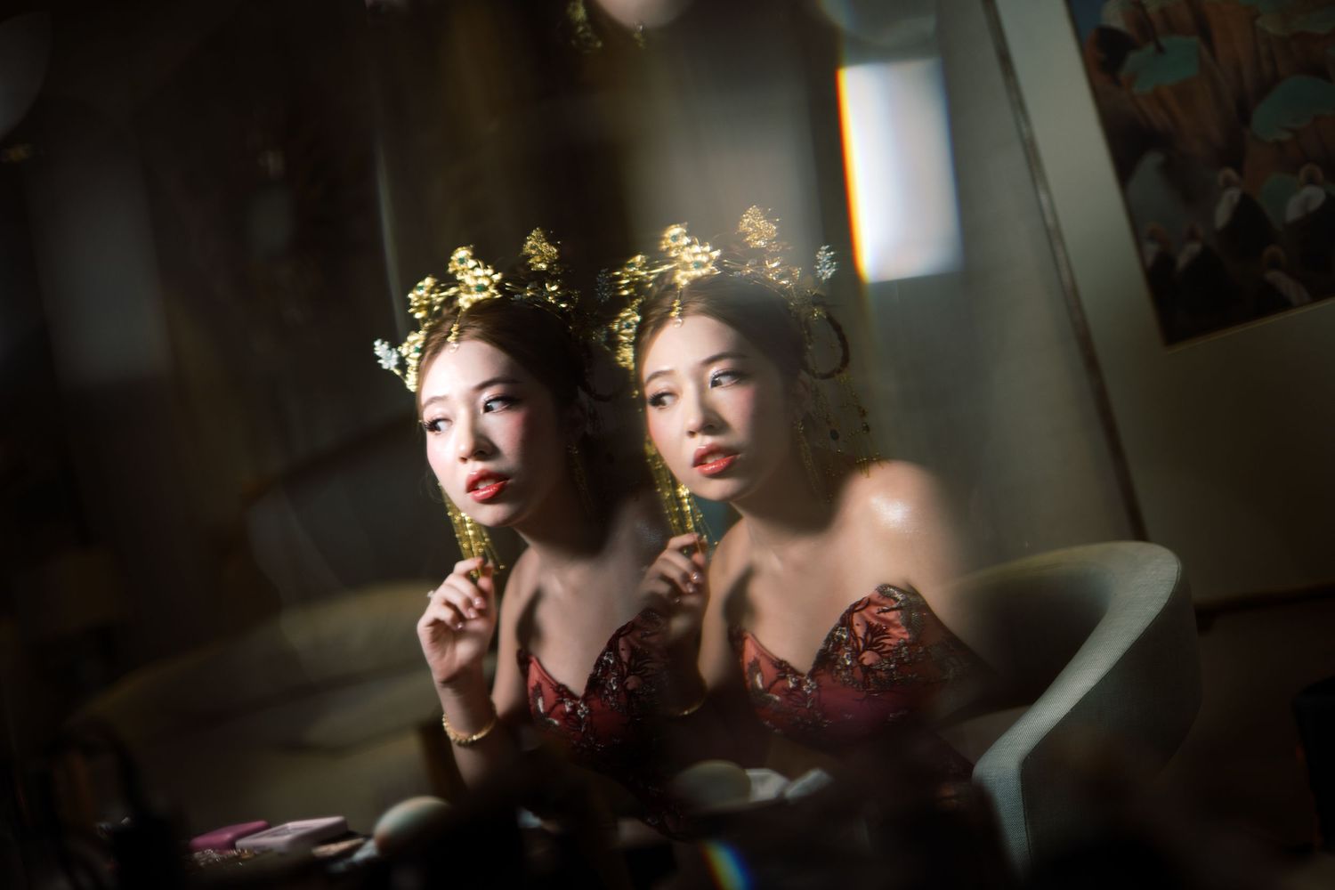 Two performers in ornate golden crowns and matching burgundy costumes pose together in an artistic portrait setting.