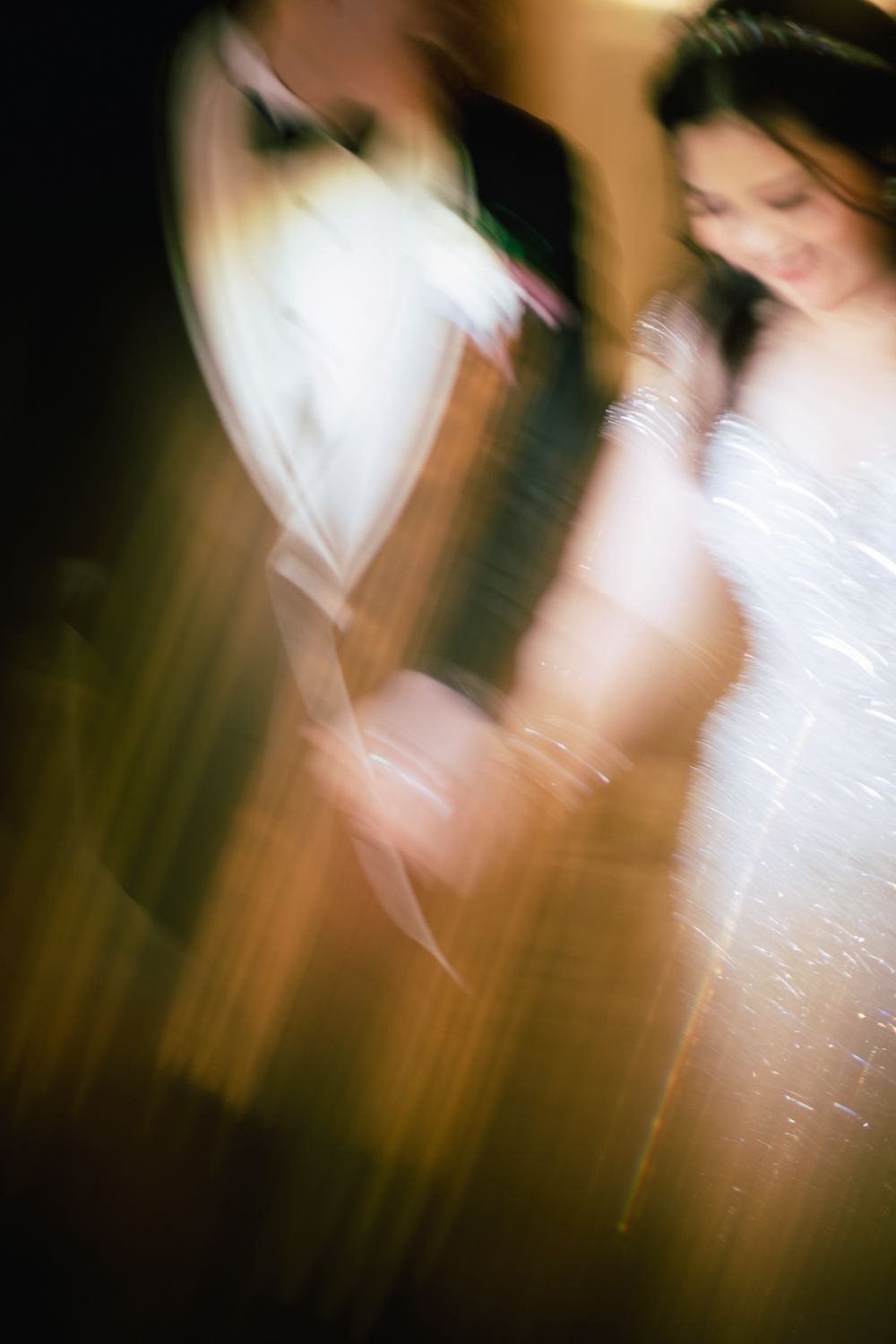 Blurred motion shot of a bride and groom sharing a dance, captured with an artistic long exposure effect.