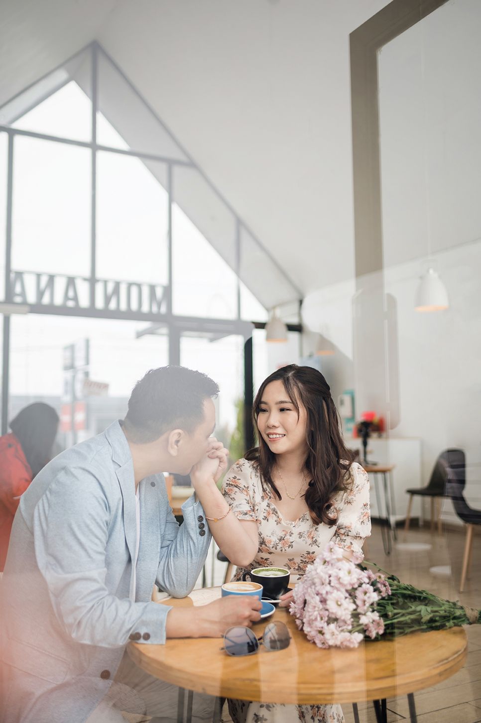A couple enjoys a romantic coffee date at a cozy cafe, with the woman smiling warmly at her partner.