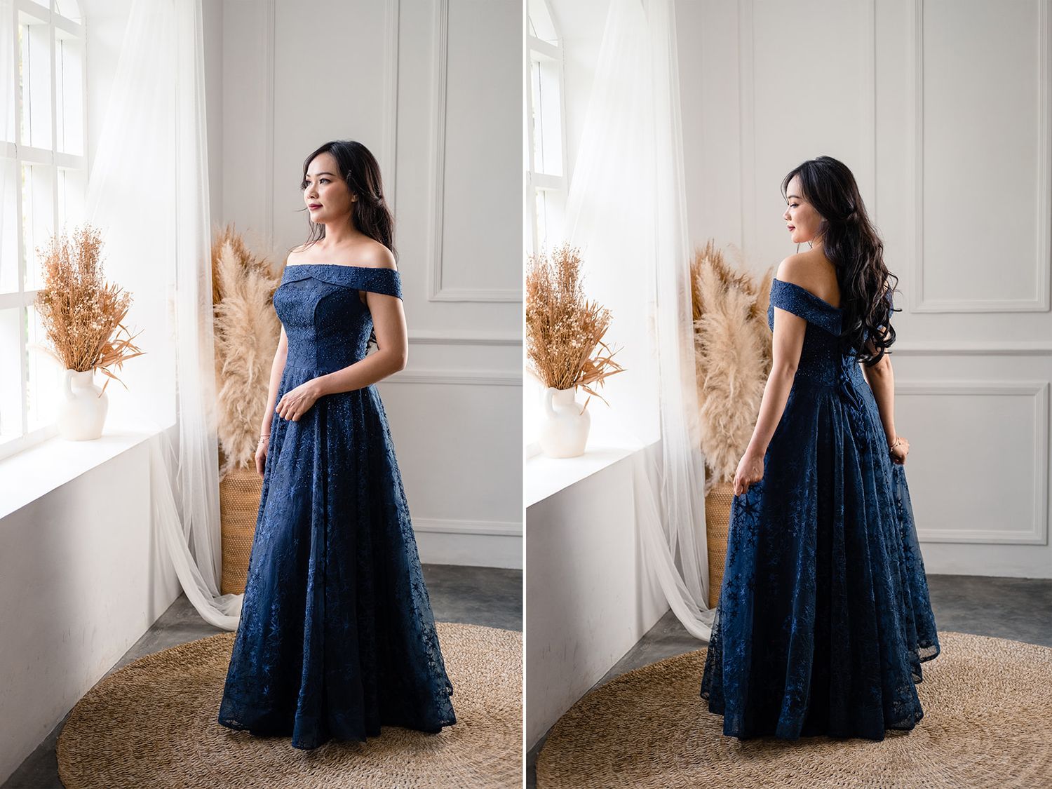 Woman in navy blue off-shoulder lace ball gown posing elegantly in a bright studio setting.