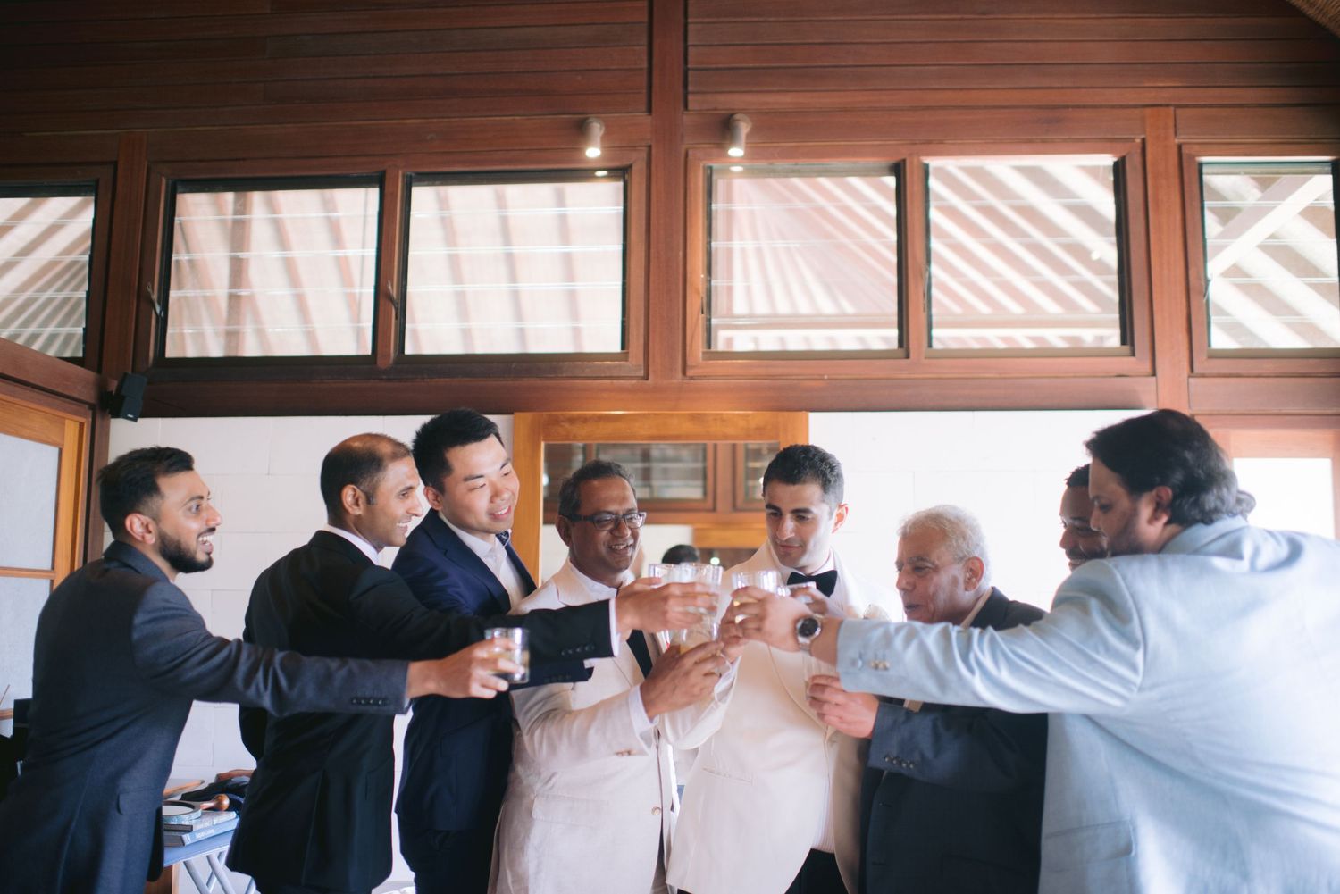 Groomsmen raising a toast together in a rustic venue during wedding preparations.