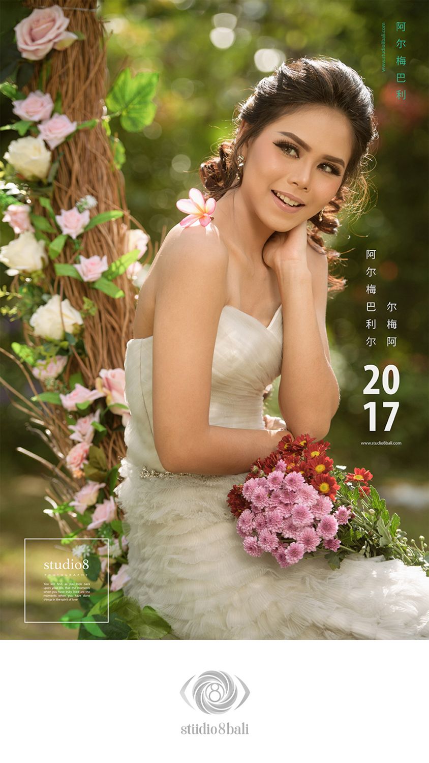 A smiling bride in a white strapless gown holds colorful flowers, posed among roses in a lush garden setting for Studio 8 Bali.