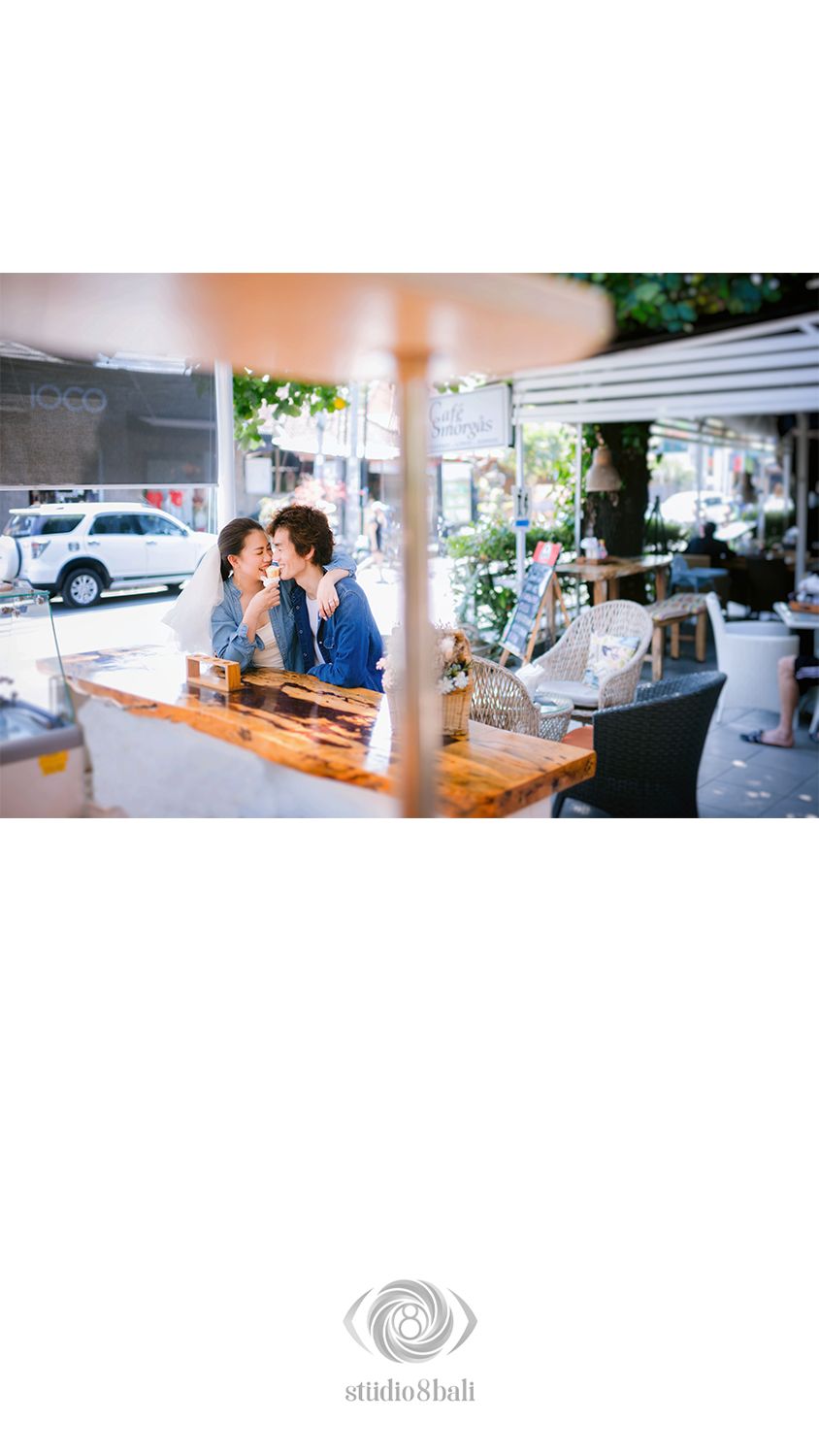 Couple sharing a tender moment at a cafe window seat, photographed by Studio 8 Bali.