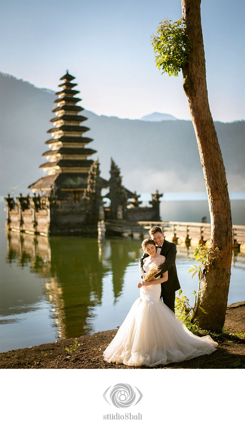 Couple in wedding attire poses near Pura Ulun Danu Bratan temple on Lake Beratan in Bali, Indonesia.