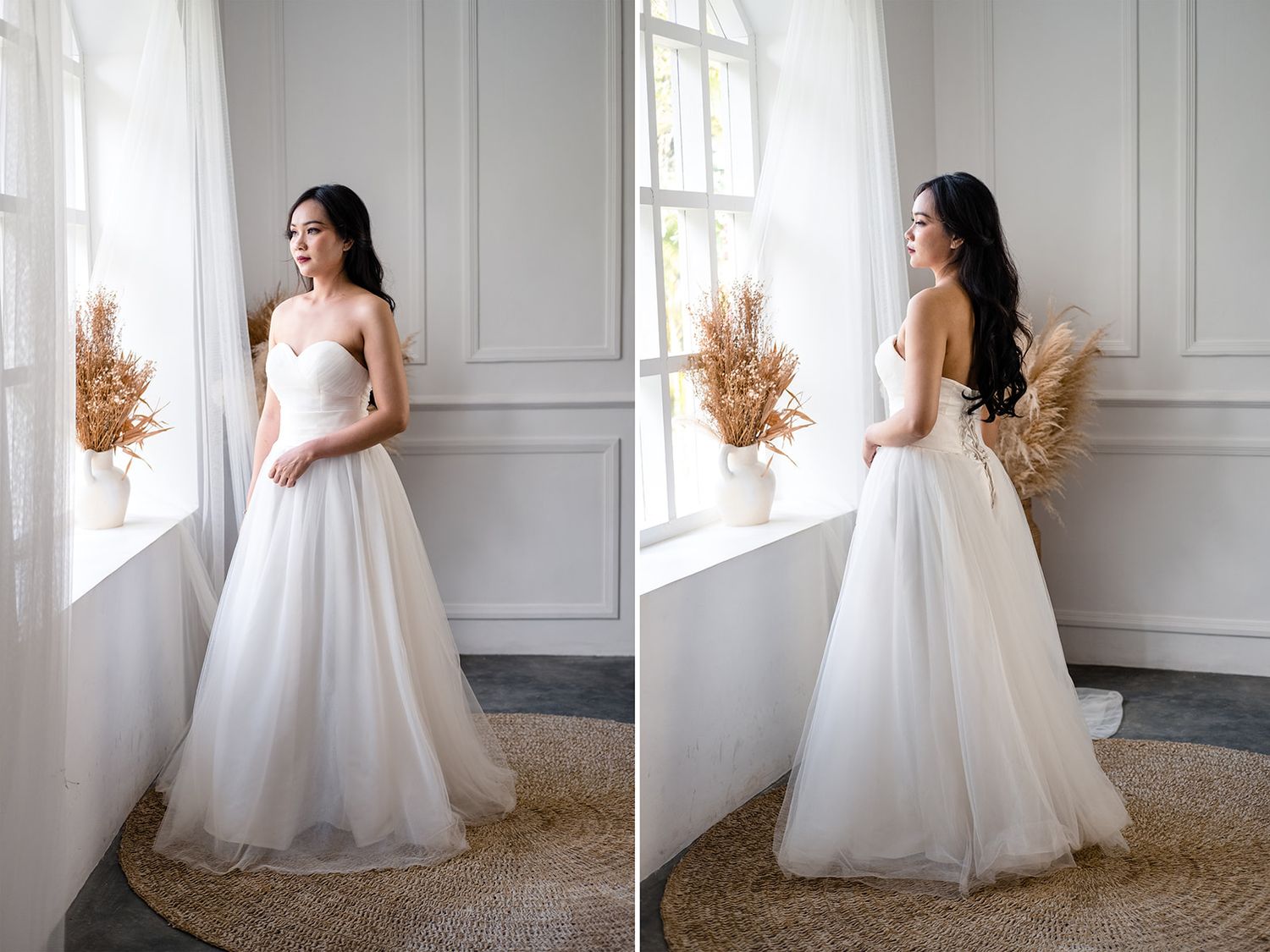 Elegant bride in a strapless white tulle ball gown standing by a bright window with dried floral arrangement.