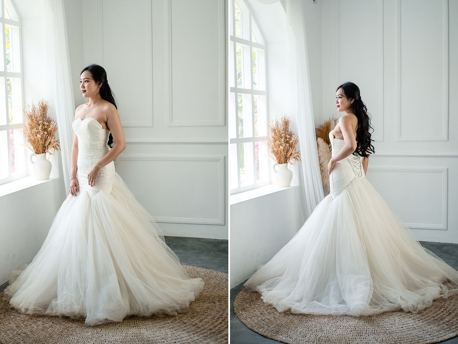 Bride in strapless mermaid tulle wedding gown with floral detail posing elegantly by bright window.