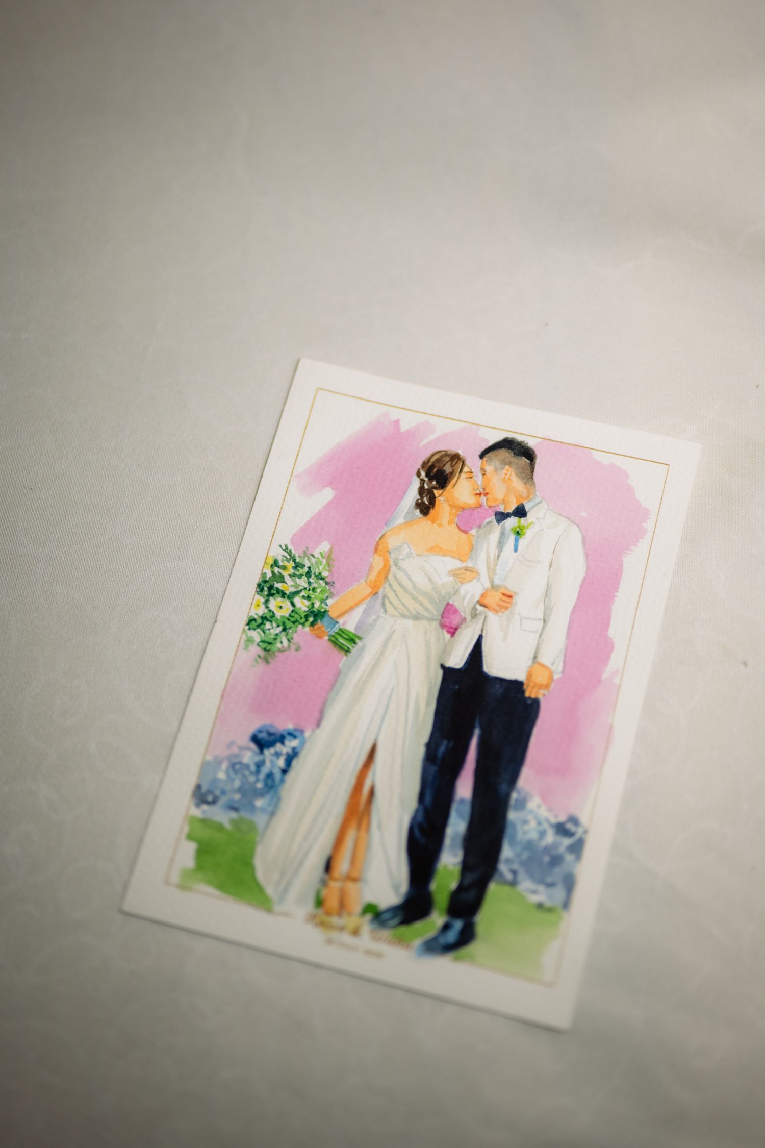 Watercolor wedding illustration of a bride in a white gown holding a bouquet and a groom in a white jacket sharing a kiss.