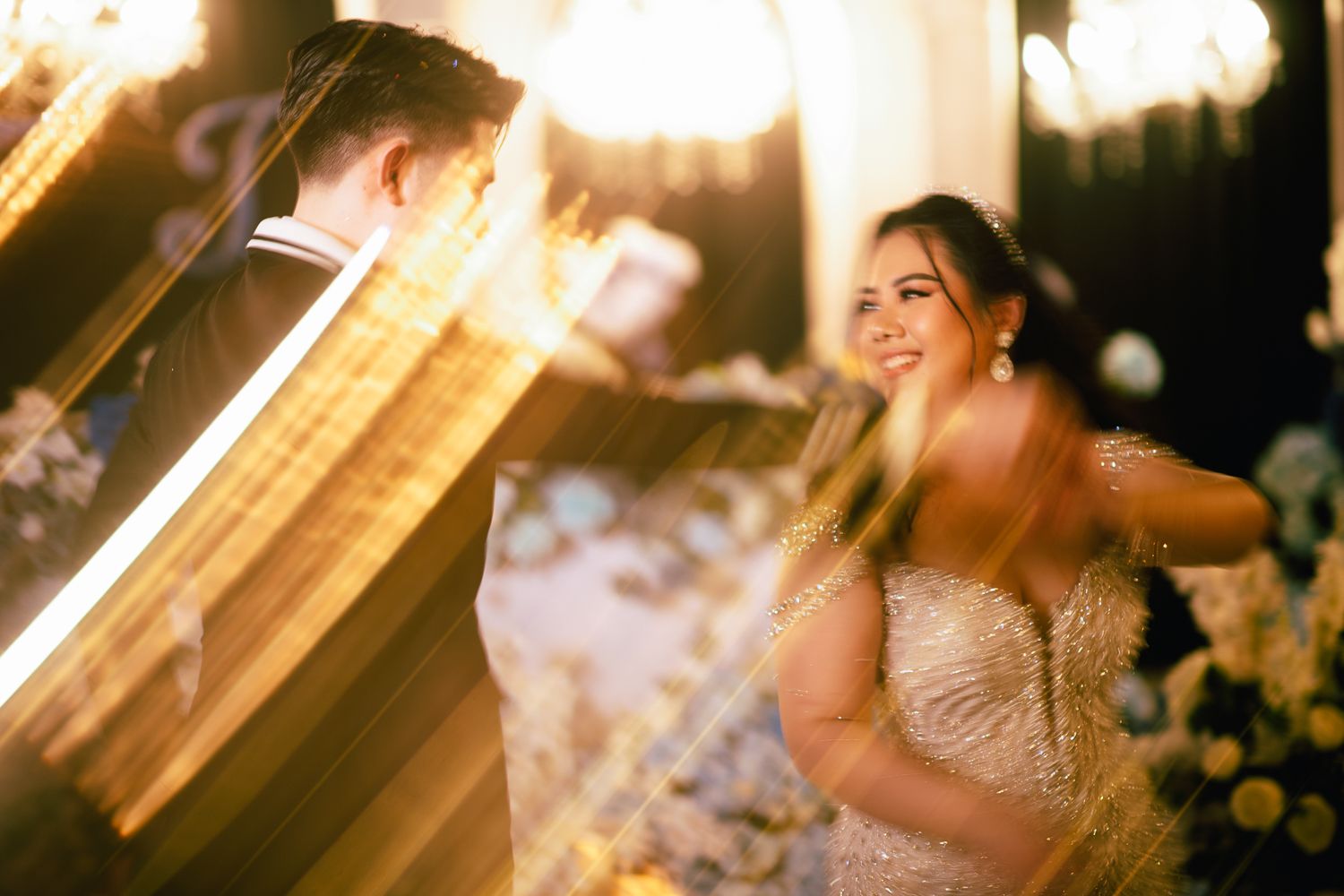 Bride and groom share a romantic first dance surrounded by glowing sparklers and warm bokeh lights at their wedding reception.
