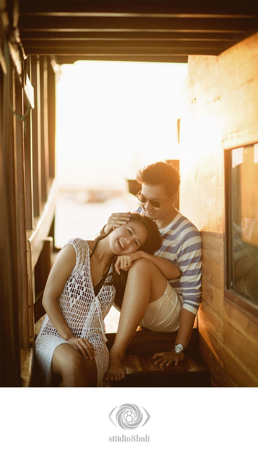 Couple sharing a romantic moment at golden hour, smiling and leaning together in a warm sunlit doorway.