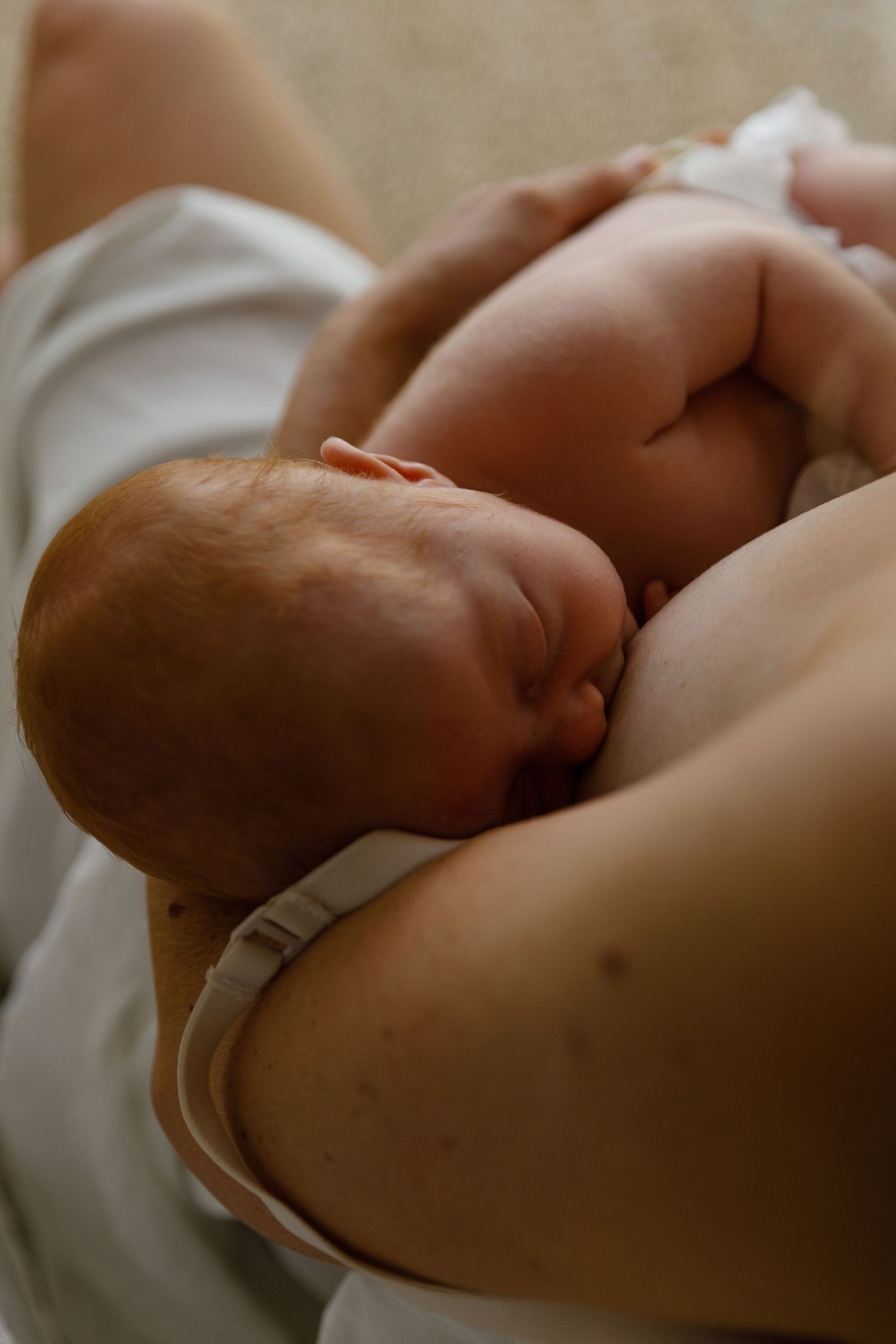 Mother breastfeeding her newborn baby, cradling the infant gently in her arms in a tender bonding moment.