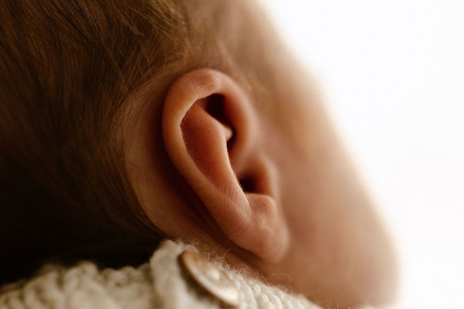Close-up of a newborn baby's delicate ear showing fine details of infant skin and ear anatomy.