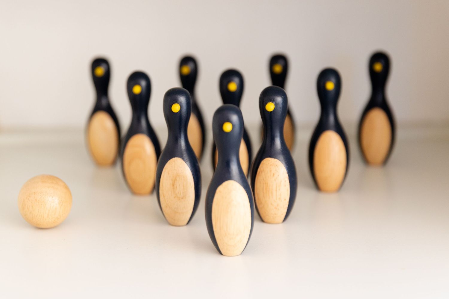 Miniature wooden bowling set with ten black and tan pins arranged in formation with a small wooden ball in the foreground.