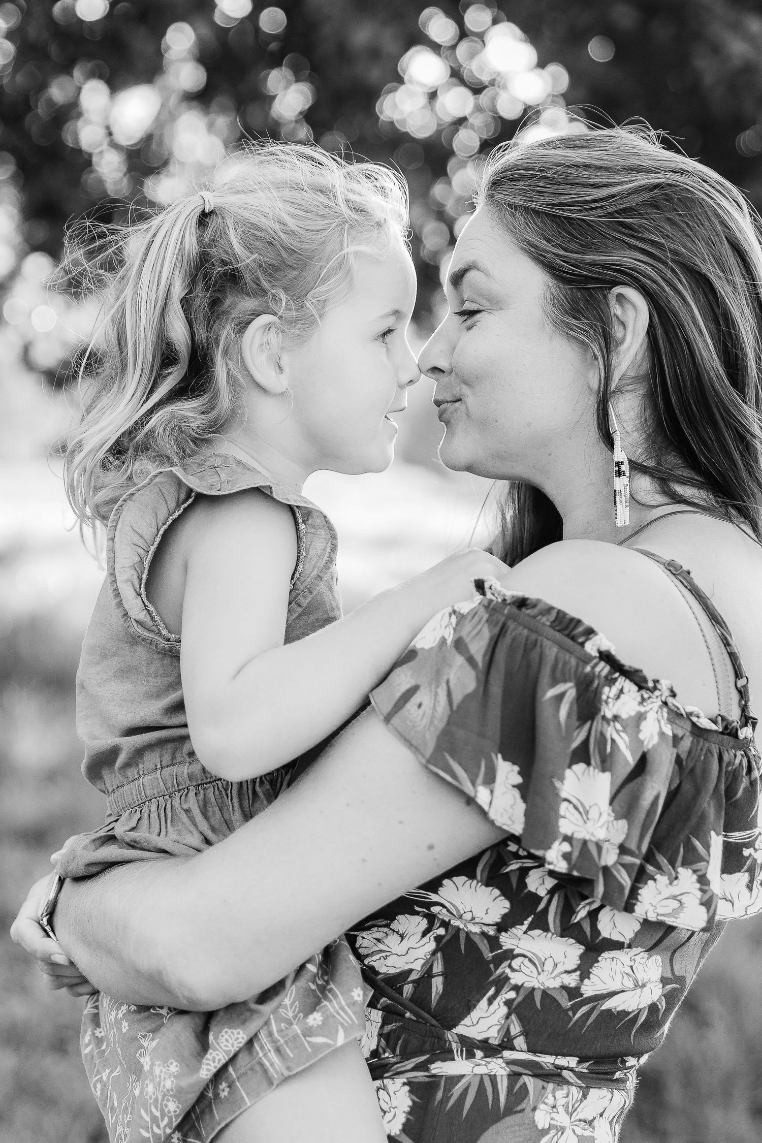 Black and white photo of a mother and young daughter sharing a tender nose-to-nose moment.