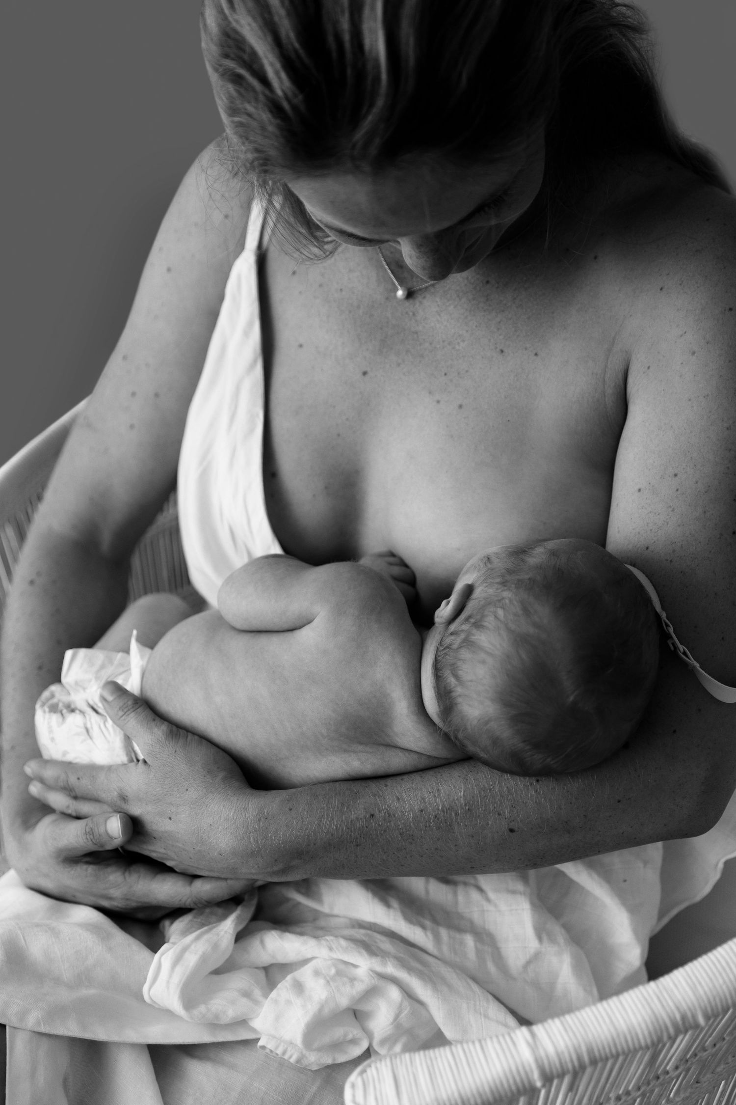 Black and white photo of a mother breastfeeding her newborn baby, cradling the infant tenderly in her arms.