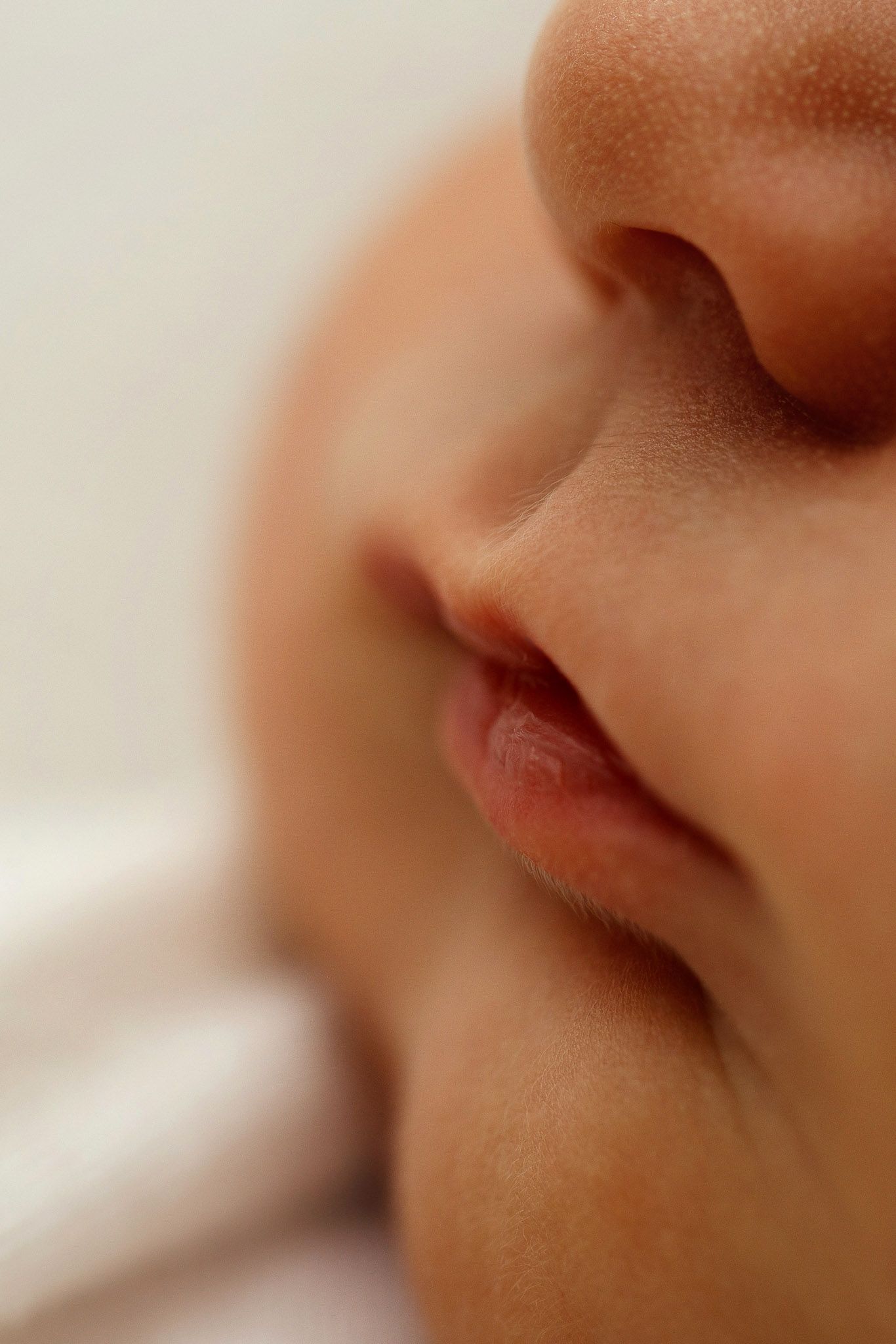 Close-up macro photo of a baby's nose and lips, showcasing soft delicate skin texture.