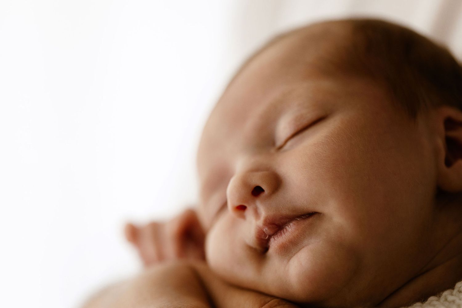 Close-up portrait of a peaceful sleeping newborn baby with soft natural lighting.
