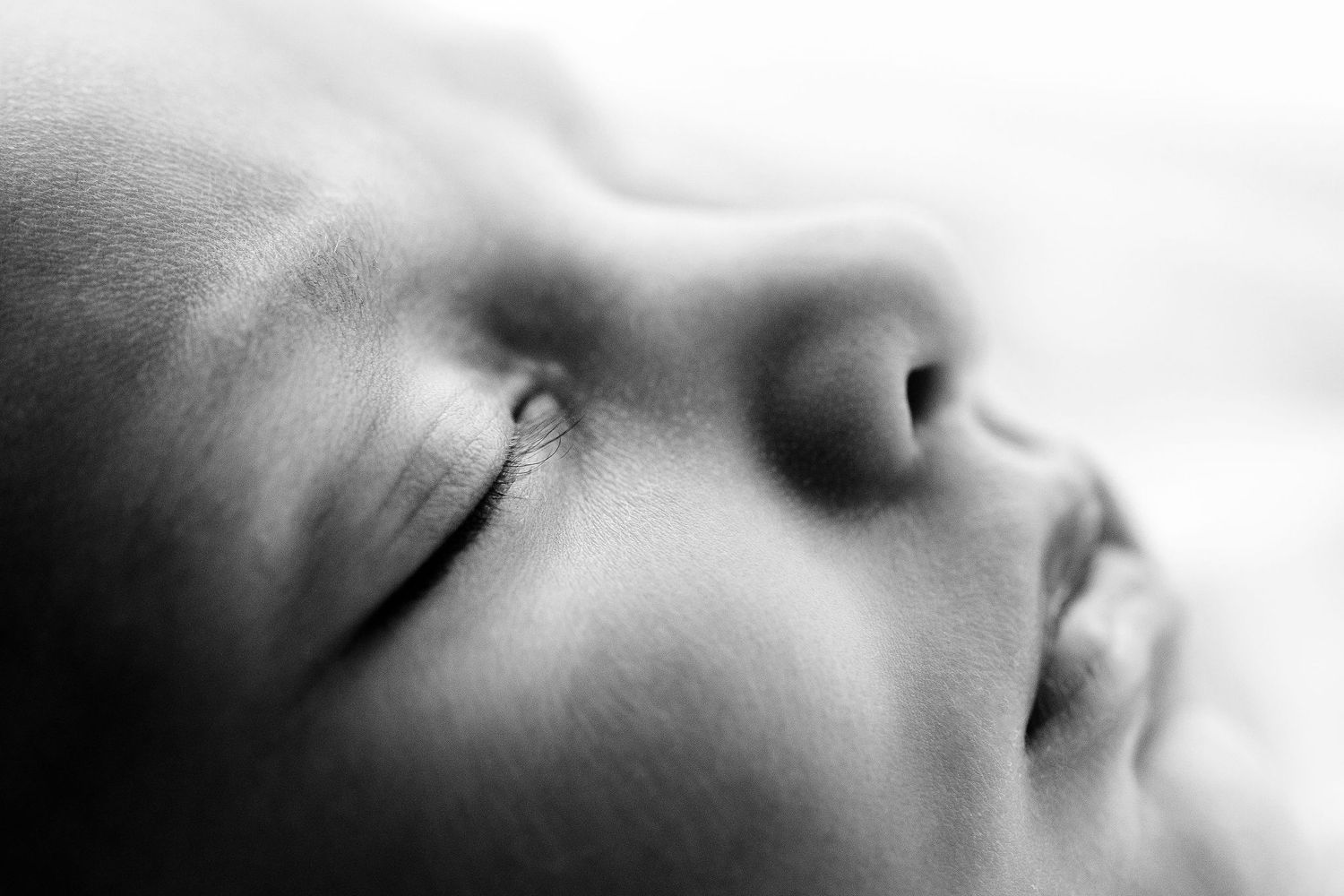 Extreme close-up black and white macro photo of a peaceful sleeping newborn baby's face.