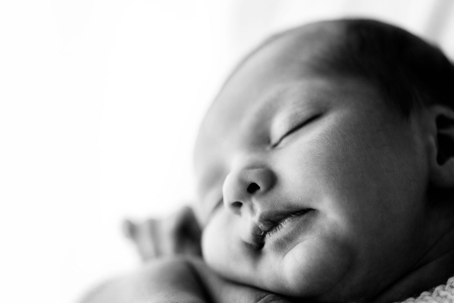 Close-up black and white portrait of a peaceful sleeping newborn baby.
