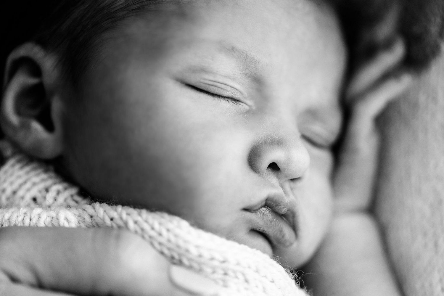 Close-up black and white photo of a peaceful sleeping newborn baby.