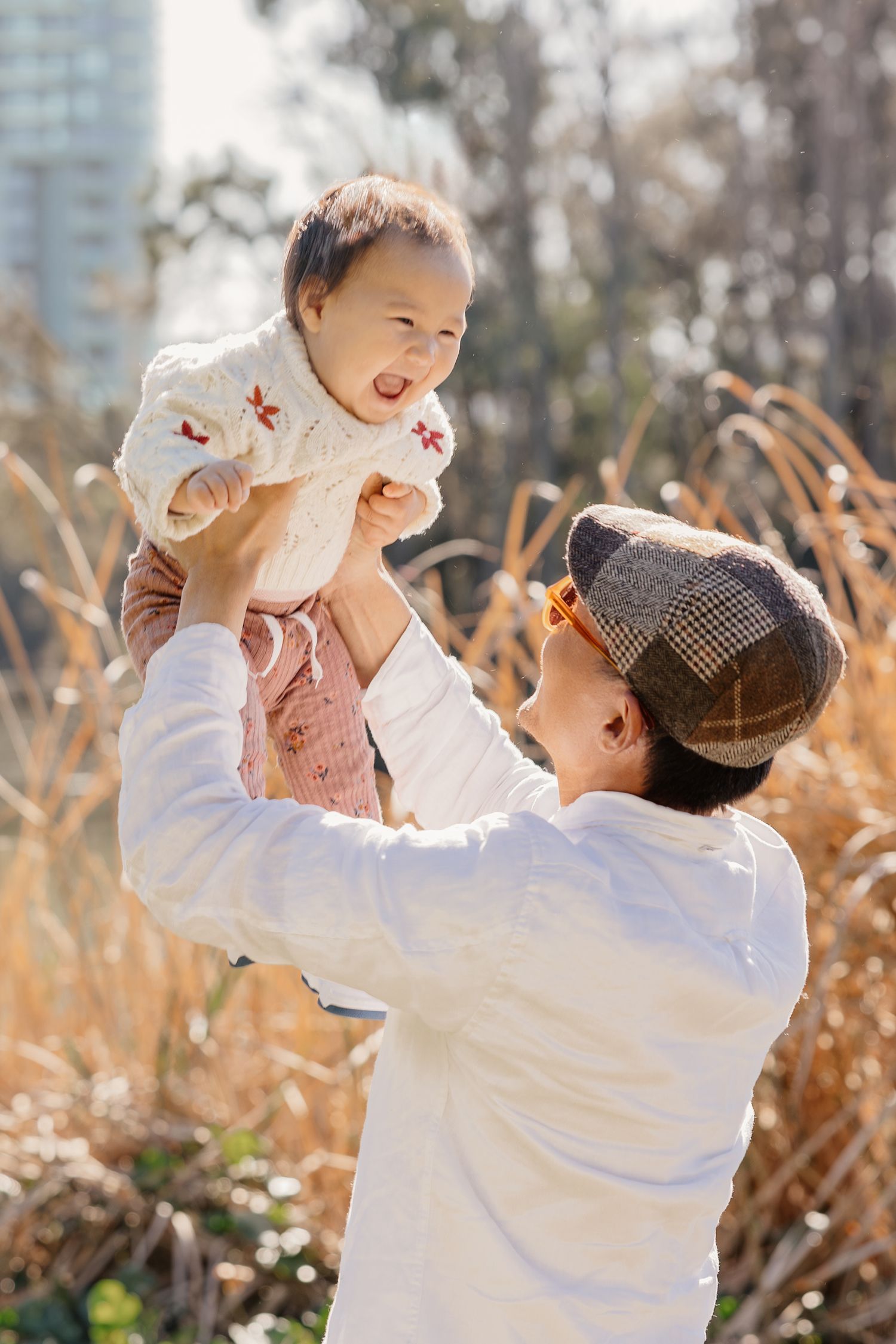 Father lifting baby outdoors in golden light, Sydney family photographer
