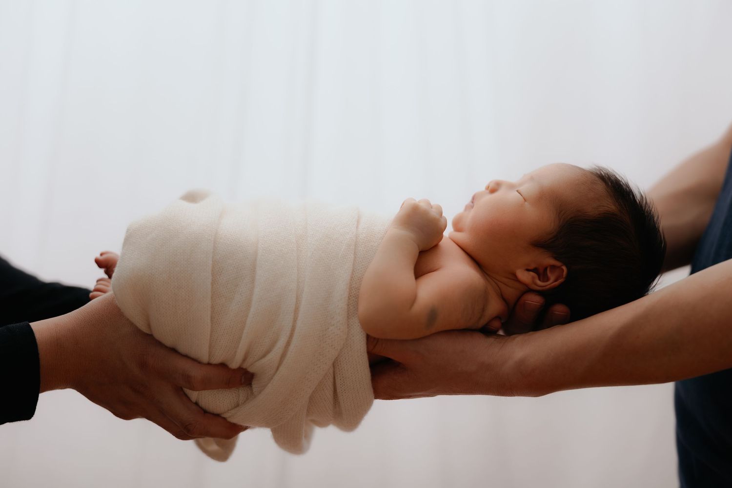 Newborn baby wrapped and held in parents’ hands, lifestyle newborn session Sydney