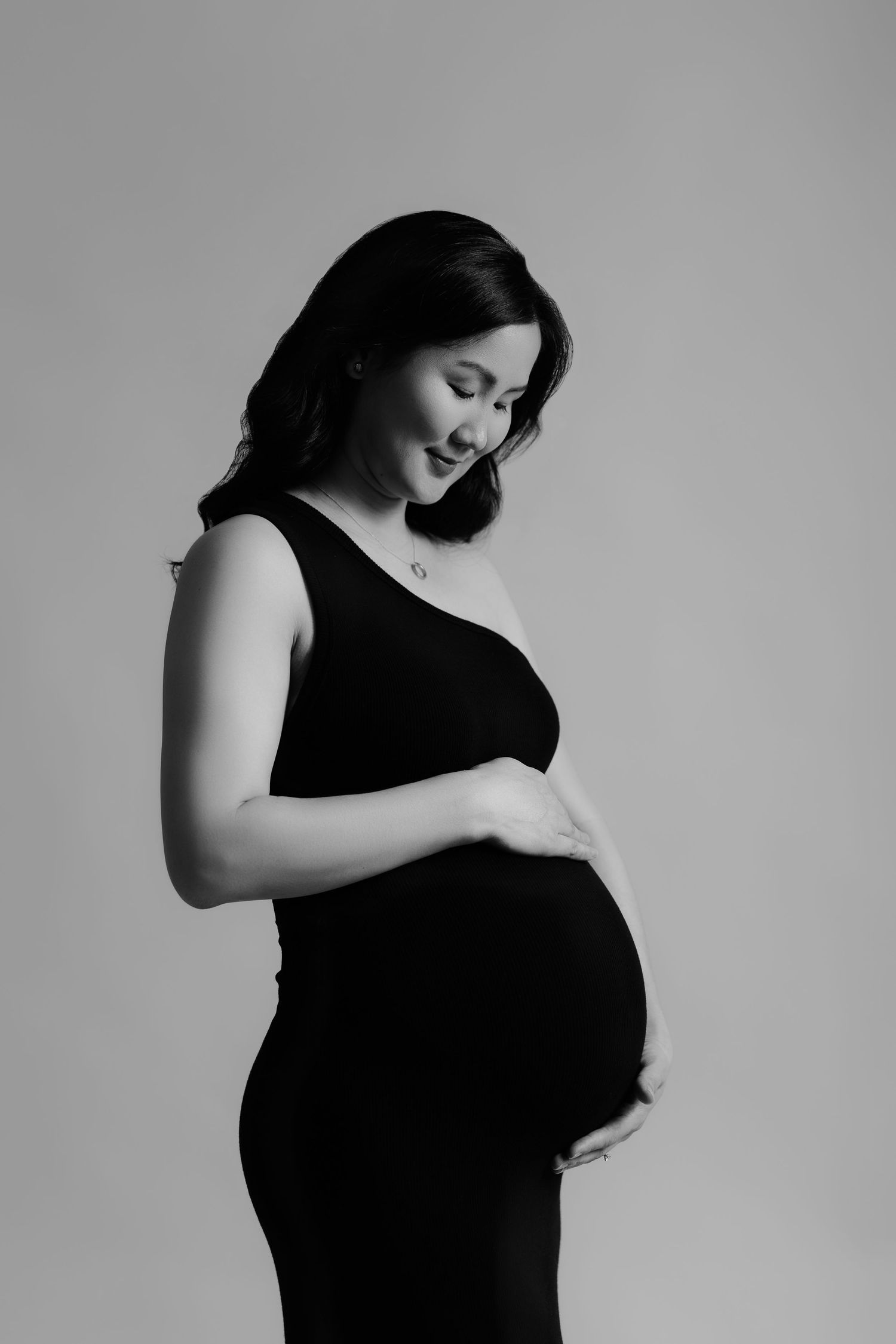 Studio maternity portrait in black dress looking down, Sydney maternity photographer