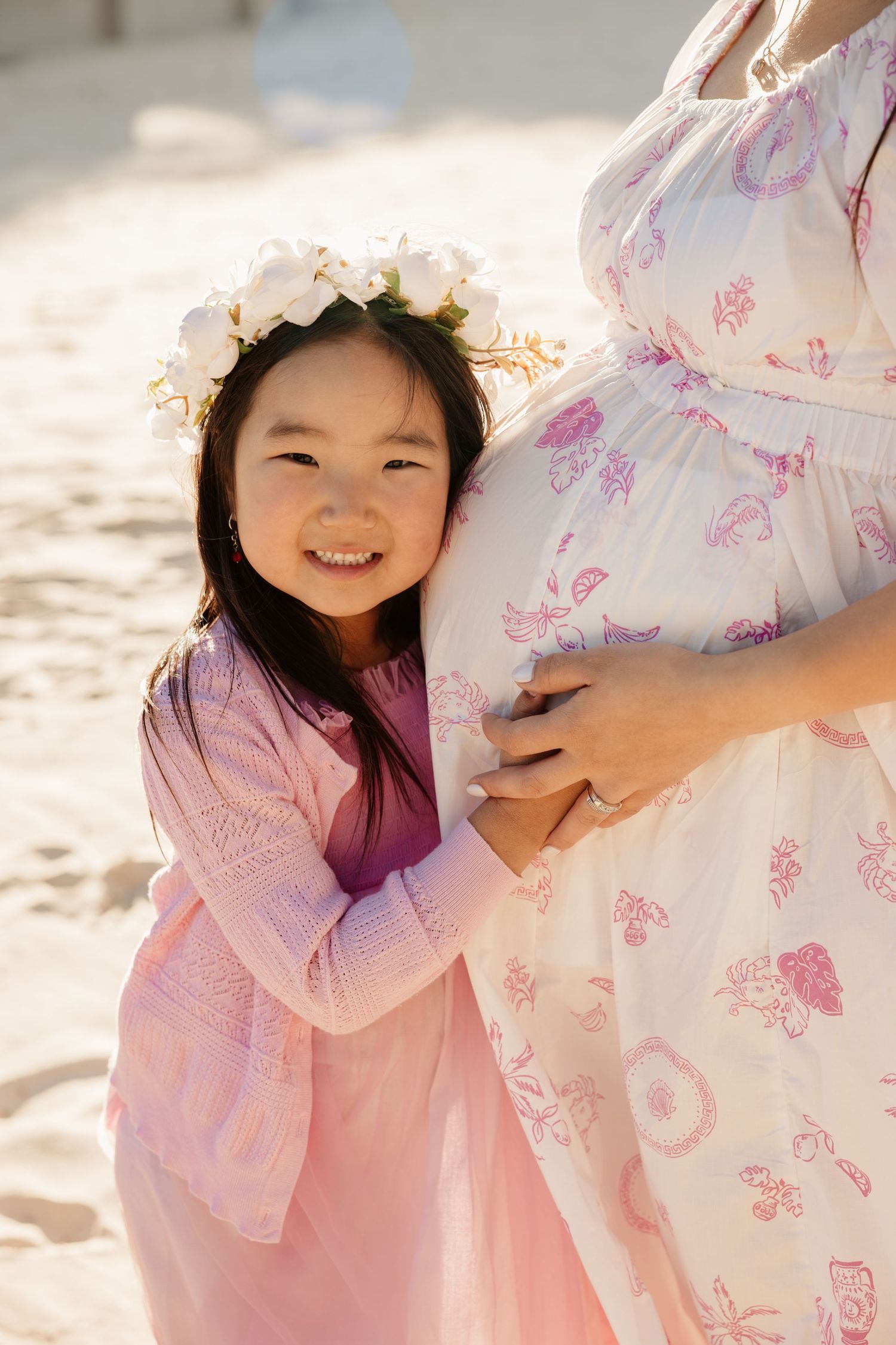 Child smiling beside pregnant mother at beach, Sydney maternity family photography