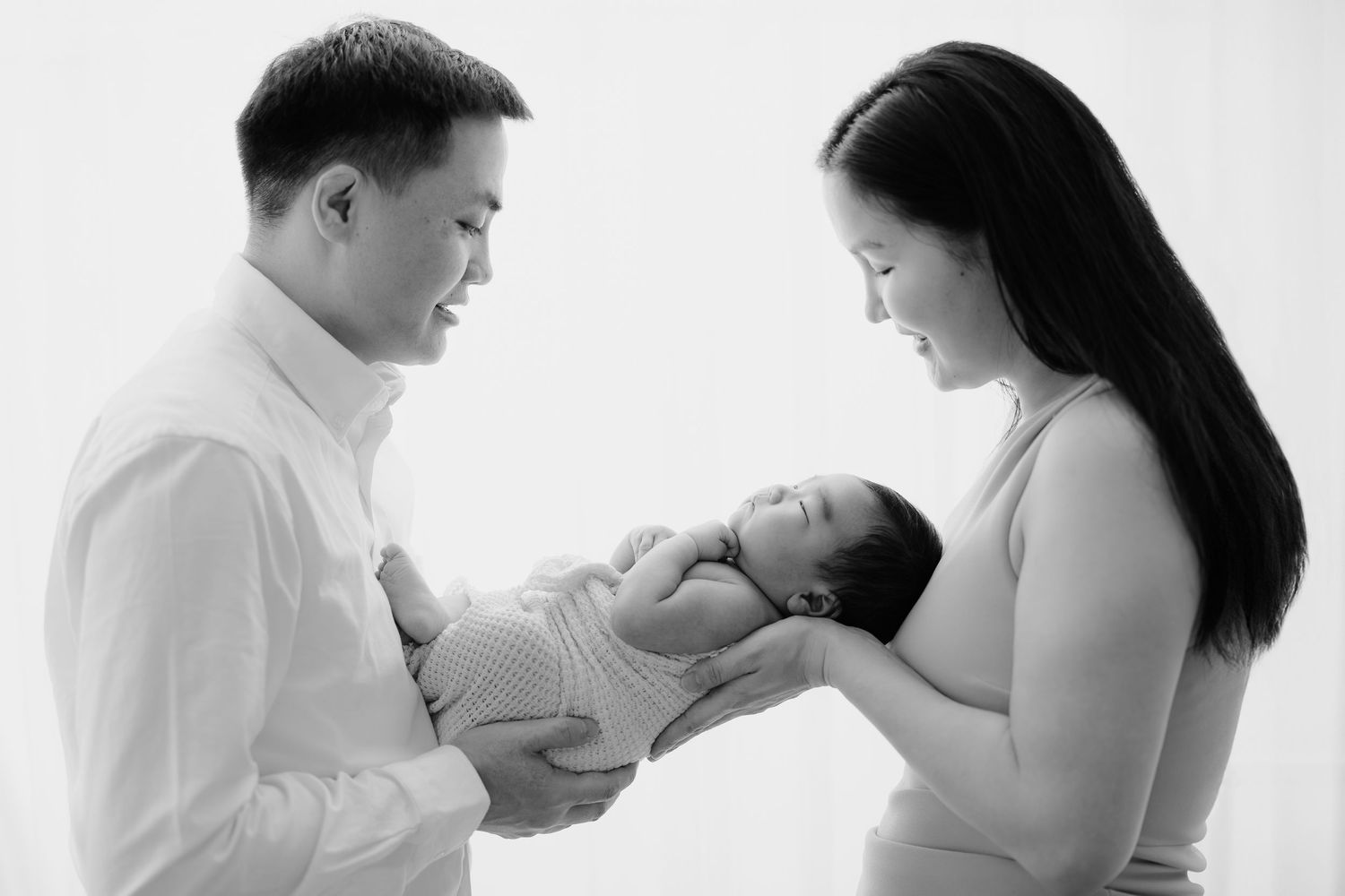 Black and white studio newborn portrait of parents holding their baby, Sydney newborn photography