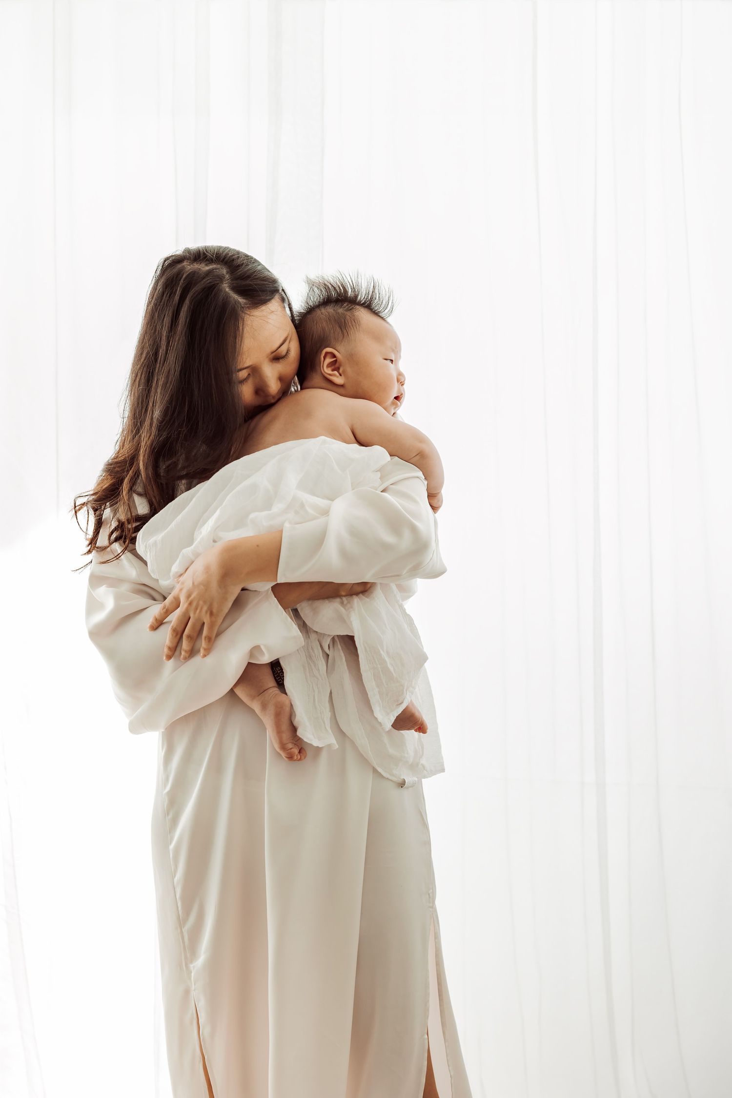 Lifestyle portrait of mother holding baby in soft window light, Sydney newborn photography