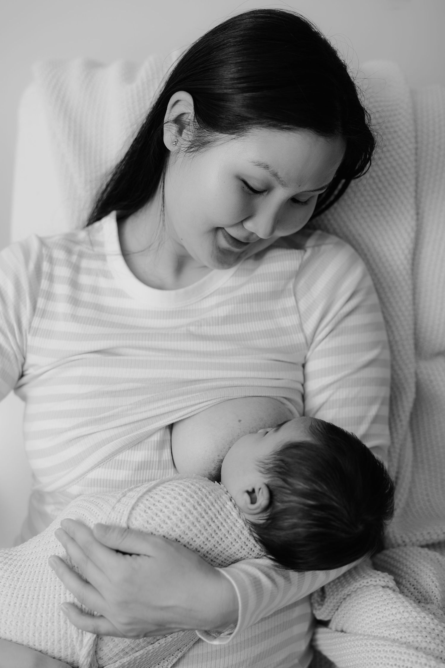 Black and white photo of mother holding newborn baby on a bed, lifestyle newborn session Sydney