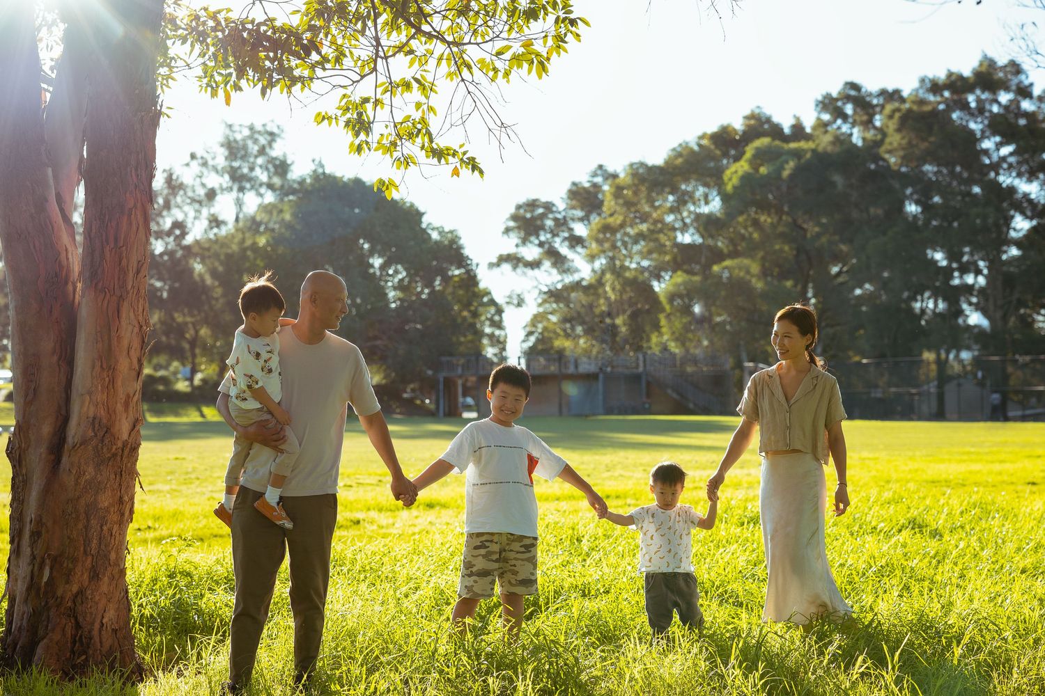 Family holding hands walking through a sunny park, Sydney outdoor family photography